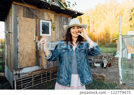 With a beaming smile, a hobby woman farmer displays a perfect egg Delightful farm scene as a cheerful woman showcases her freshly collected egg Sustainable lifestyle, organic farmer, With a beaming smile, a hobby woman farmer displays a perfect egg Delightful farm scene as a cheerful woman showcases her freshly collected egg Sustainable lifestyle, organic farmer, 112779075