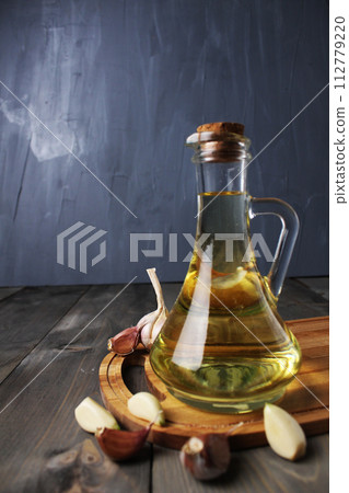 Fragrant vegetable oil with garlic and black red pepper on a gray background with space for copyspace text. Vertical Photo Fragrant vegetable oil with garlic and black red pepper on a gray background with space for copyspace text. Vertical Photo 112779220