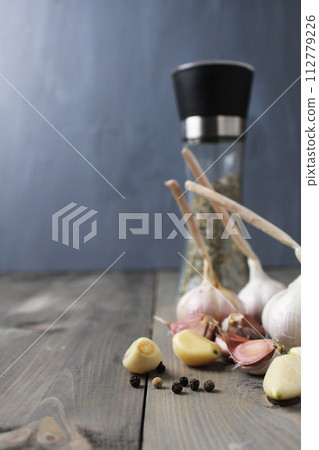 Peeled garlic and heads of white purple garlic on gray foon with space for salt shaker text 112779226
