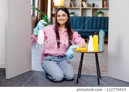 Young woman sitting near the table with cleaning products at home. 112779423