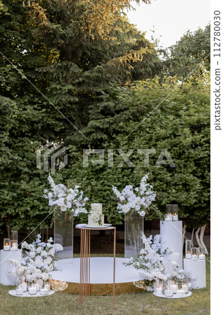 a wedding cake near arch for the evening ceremony 112780030