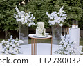 a wedding cake near arch for the evening ceremony 112780032