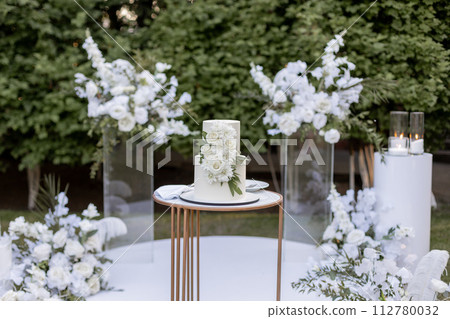 a wedding cake near arch for the evening ceremony 112780032