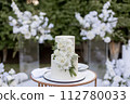 a wedding cake near arch for the evening ceremony 112780033