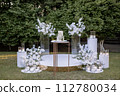 a wedding cake near arch for the evening ceremony 112780034