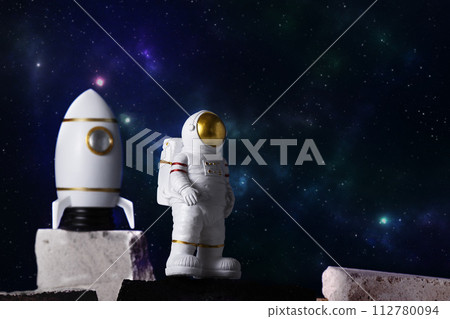 Figurine of astronaut and rocket over sky background, copy space. Toy of spaceman and cosmos shuttle. Space and space flights concept. Day of cosmonauts. 112780094