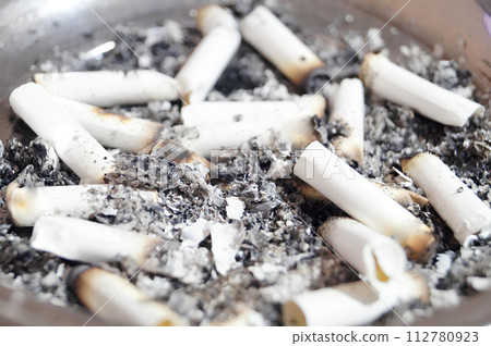 A pile of burnt cigarette butts in a pan A pile of burnt cigarette butts in a pan 112780923