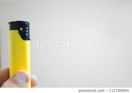 A person is holding a yellow lighter 112780964