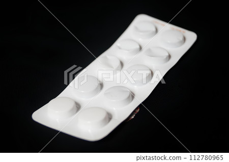 A white pill bottle with a white pill inside 112780965