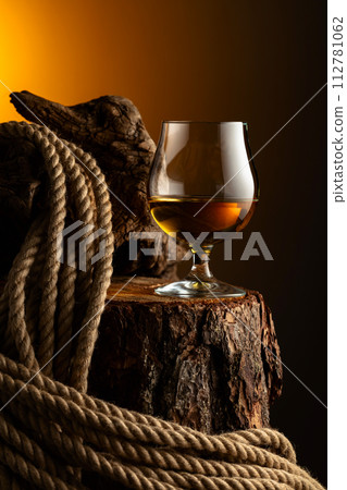 Brandy snifter and rope on a old stumb. 112781062