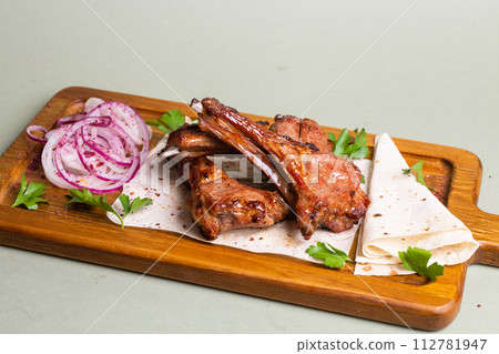 Grilled lamb ribs with herbs and spices on a wooden board 112781947