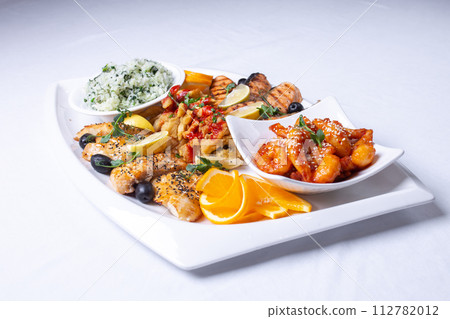 seafood mixture on a white grill. Delicious grilled fish, shrimp in sauce and salmon on the table 112782012