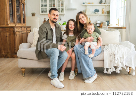 Happy family at home. Mother father two children daughters relaxing on sofa indoor. Mom dad parents baby girls kids relax playing having fun together. Family smiling laughing enjoying tender moment Happy family at home. Mother father two children daughters relaxing on sofa indoor. Mom dad parents baby girls kids relax playing having fun together. Family smiling laughing enjoying tender moment 112782198