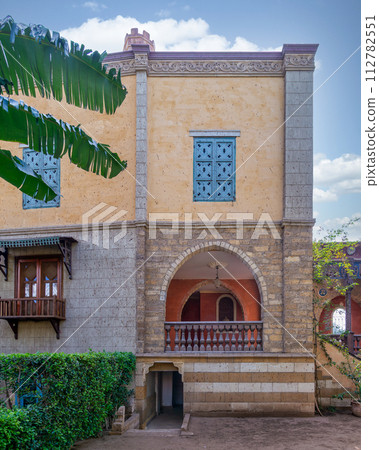 Serene view of a rustic style building featuring an arched wooden balcony, and detailed window grills 112782551