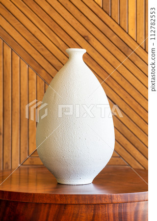 Minimalist White Ceramic Vase Against Wooden cladding Minimalist White Ceramic Vase Against Wooden cladding 112782553