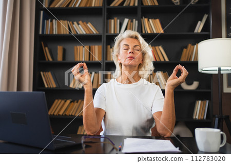 Yoga mindfulness meditation No stress keep calm. Middle aged woman practicing yoga at office. Woman taking break from work meditating relaxing. Mature lady doing breathing practice online yoga at work Yoga mindfulness meditation No stress keep calm. Middle aged woman practicing yoga at office. Woman taking break from work meditating relaxing. Mature lady doing breathing practice online yoga at work 112783020