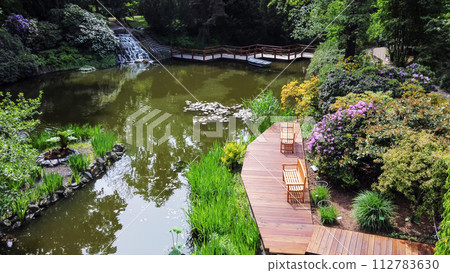 Amazing view on Wroclaw Botanical garden with pond and zigzag bridge and interesting waterfall Amazing view on Wroclaw Botanical garden with pond and zigzag bridge and interesting waterfall 112783630