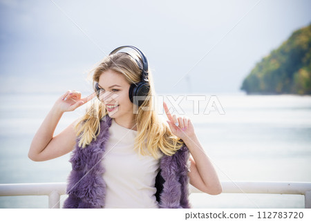 Happy woman wearing headphones outdoor 112783720