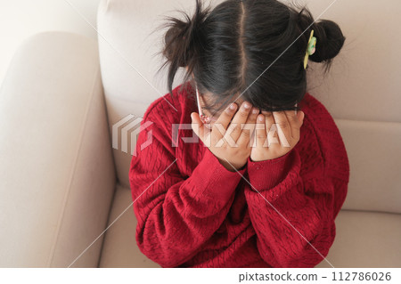 a upset child girl cover her face with hand  112786026
