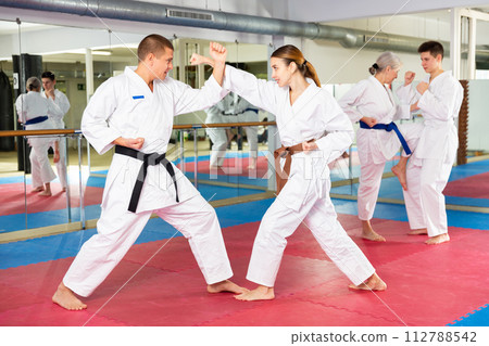 Girl in kimono practicing martial arts techniques paired with trainer Girl in kimono practicing martial arts techniques paired with trainer 112788542