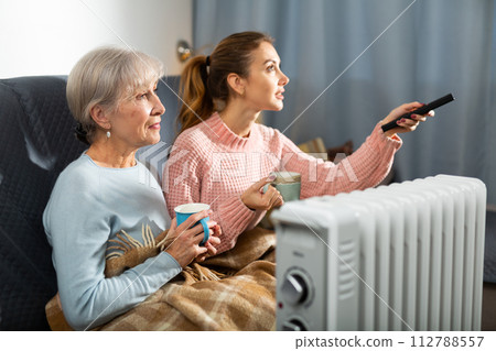 Positive girl with aged mother watching TV on sofa Positive girl with aged mother watching TV on sofa 112788557