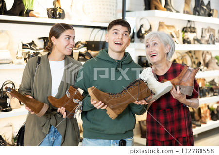 Happy family discussing models of ankle boots in shoe store Happy family discussing models of ankle boots in shoe store 112788558