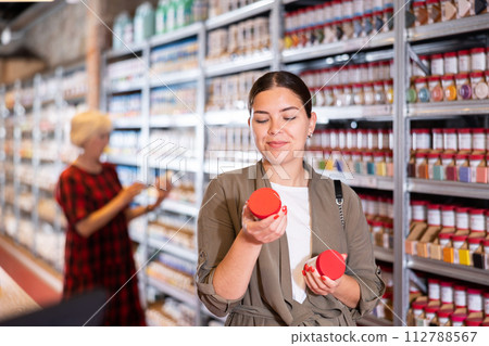 Female shopper choosing pottery glaze jars in pottery specialty store 112788567