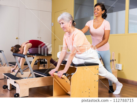 Mature woman trains on a combined chair with instructor Mature woman trains on a combined chair with instructor 112788715