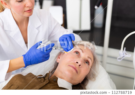 Elderly woman recieving botulinotherapy for her face Elderly woman recieving botulinotherapy for her face 112788719
