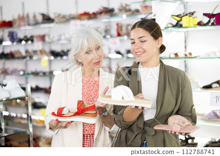 Two female friends and colleagues consult with each other about buying flip-flops or sandals Two female friends and colleagues consult with each other about buying flip-flops or sandals 112788741