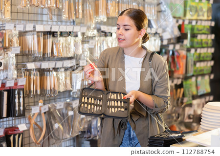 Young woman chooses a set of tools for working with clay in specialized store Young woman chooses a set of tools for working with clay in specialized store 112788754