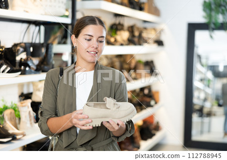 Girl buyer looks at footwear from new collection and picks up new pair of moccasins shoes 112788945