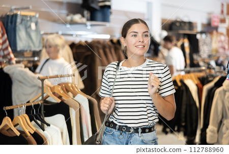 Young woman carefully examines garments 112788960