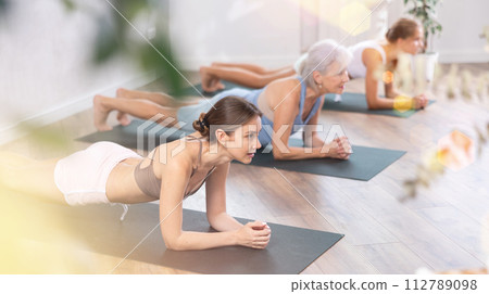 Women of different generations yoga showing plank pose in wellness center Women of different generations yoga showing plank pose in wellness center 112789098