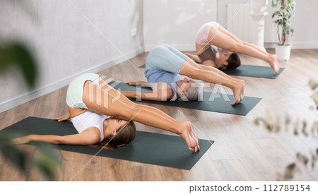 Mom, grandma and teenage daughter do Halasana plow pose. 112789154