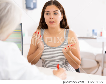 Young woman patient discussing face aesthetic procedures with a specialist Young woman patient discussing face aesthetic procedures with a specialist 112789177