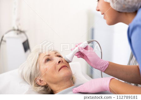 Old woman having face laser therapy procedure 112789181