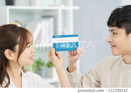 A man and a woman holding a bank passbook with a smile A man and a woman holding a bank passbook with a smile 112789187