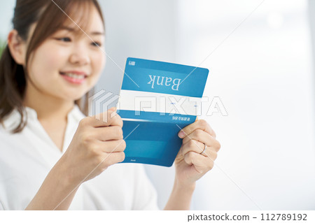 A woman looking at a bank passbook with a smile A woman looking at a bank passbook with a smile 112789192