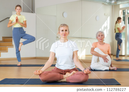 Group of women and teen girl doing yoga Padmasana exercise, Lotus pose Group of women and teen girl doing yoga Padmasana exercise, Lotus pose 112789227