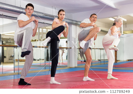 Various aged men and women training kicks during self-defence training Various aged men and women training kicks during self-defence training 112789249