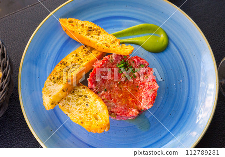 Close up of tasty veal steak tartar served at blue plate with toasts 112789281