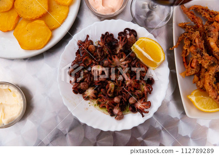 Small fried octopus with sour cream and vegetables 112789289
