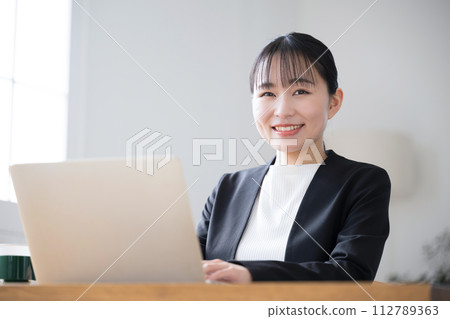 Japanese business woman operating a computer, close-up, smiling looking at the camera 112789363