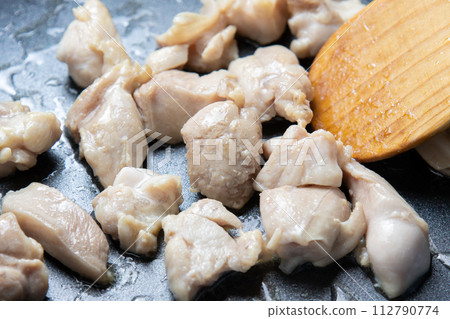 A cooking scene of frying chicken thighs in a frying pan. 112790774