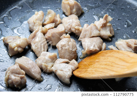 A cooking scene of frying chicken thighs in a frying pan. 112790775