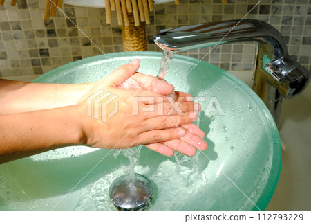 Hands of woman wash their hands in a sink with foam to wash the skin and water flows through the hands. Concept of health, cleaning and preventing germs and coronavirus from contacting hands Hands of woman wash their hands in a sink with foam to wash the skin and water flows through the hands. Concept of health, cleaning and preventing germs and coronavirus from contacting hands 112793229