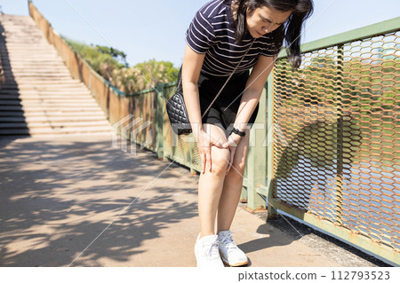 Middle aged woman walking outdoor,suffering from knee pain,Osteoarthritis of knee,Septic Arthritis,Tendinitis,Rheumatoid disease,inflammation of a tendon,degeneration of joint cartilage,health problem 112793523