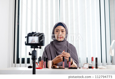 Muslim women making video beauty vlogger bloggers doing a cosmetic makeup tutorial vlog with brushes looking camera Save clips and share them on social media live via the internet Online 112794773