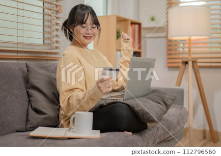 A woman is registering her credit card on a shopping website, enjoying shopping online at home. A woman is registering her credit card on a shopping website, enjoying shopping online at home. 112796560
